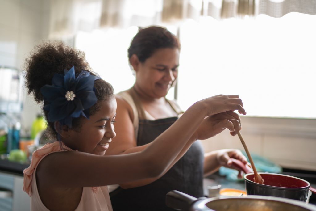 young girl & mother preparing healthy dishes for holiday meal