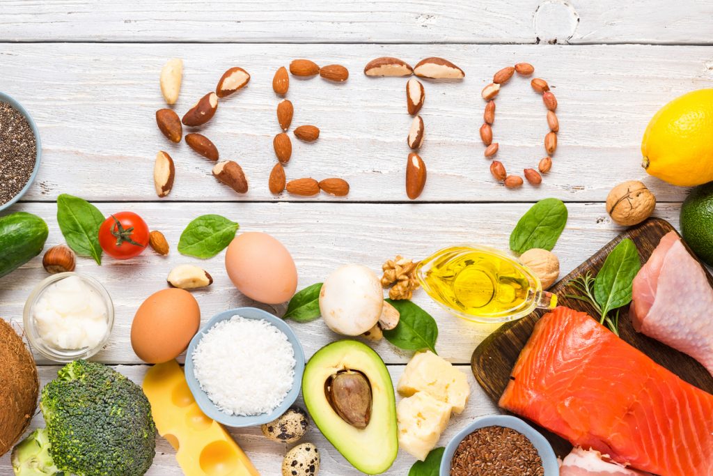 nuts spelling out KETO surrounded by keto-friendly foods: avocado, fish, etc.