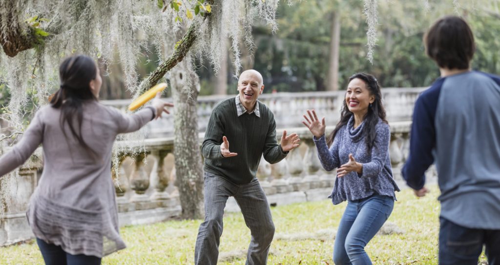 multiracial family playing frisbee in the park after a healthy holiday meal