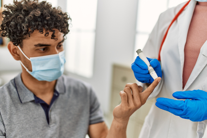 Diabetic man being administered glucose test; wearing mask as COVID precaution